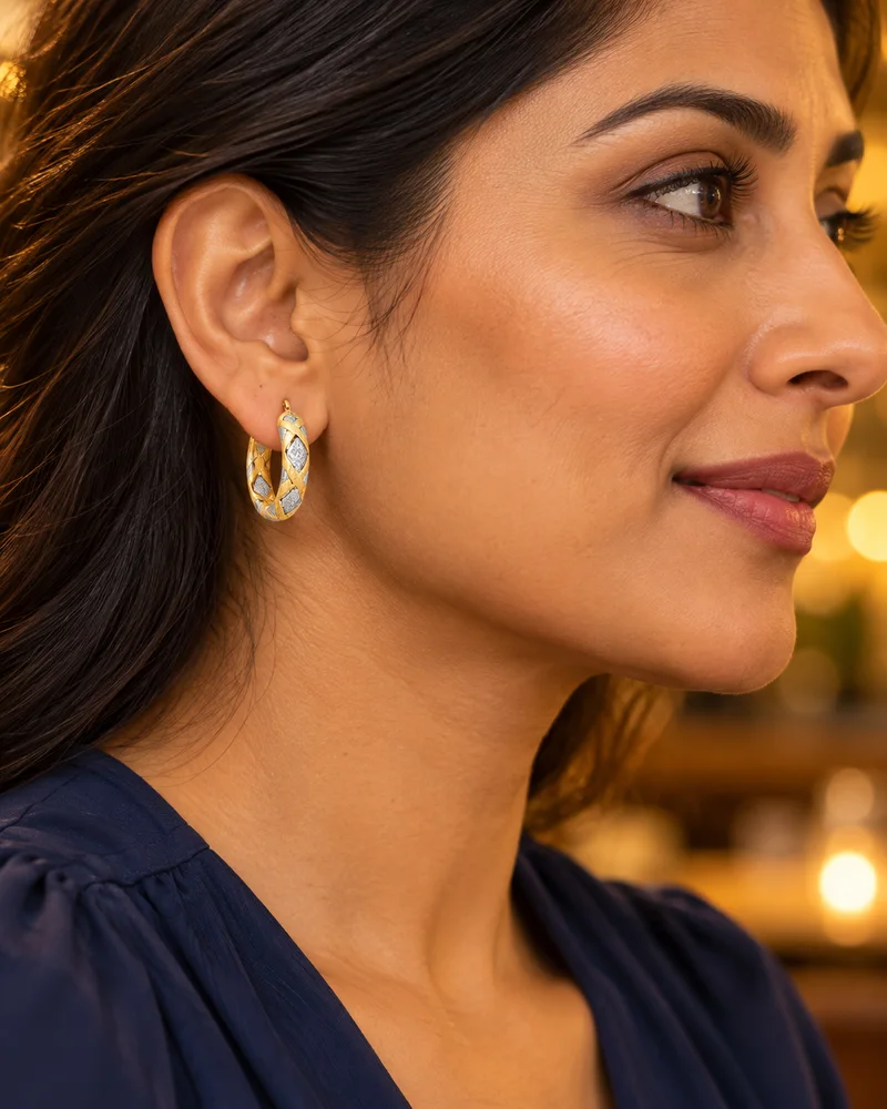 Two-tone diamond-cut X hoop earrings worn naturally in an evening look